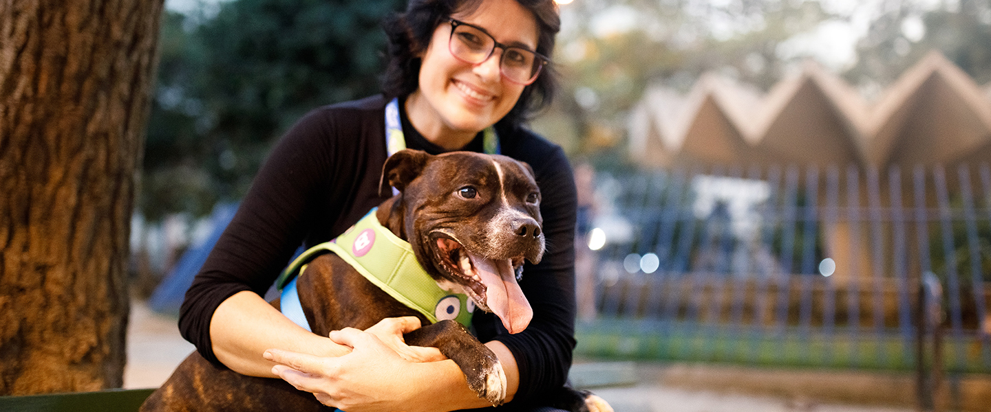 Veterinária ao ar livre abraçada com seu cachorro